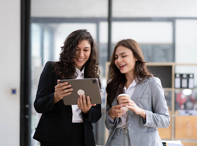 Two businesswomen standing using digital tablet consulting and analyzing information